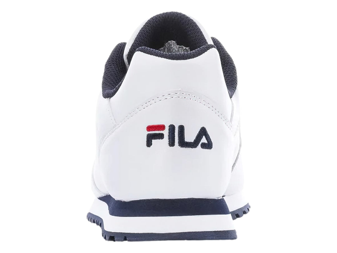 Tenis deportivos FILA de color blanco con suela azul marino y detalles en rojo.