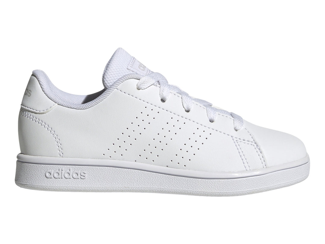 Tenis Adidas Advantage K color blanco con rayas laterales perforadas y suela plana blanca.