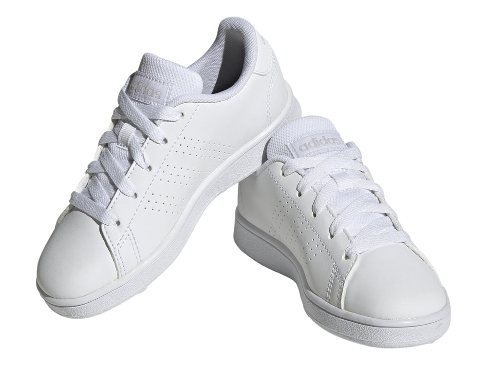 Tenis Adidas Advantage K color blanco con rayas laterales perforadas y suela plana blanca.