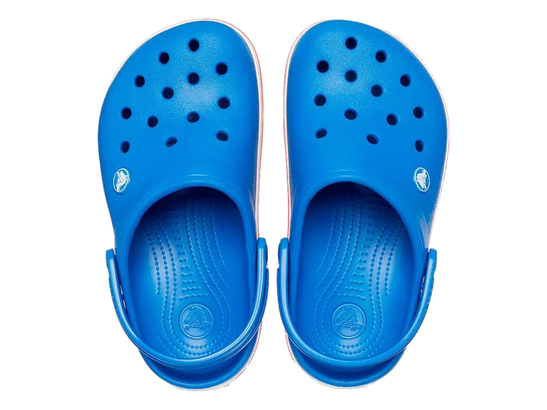 Zuecos Crocs para niños color azul con franjas blancas y rojas en la suela.