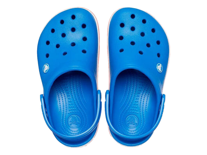 Zuecos Crocs para niños color azul con franjas blancas y rojas en la suela.