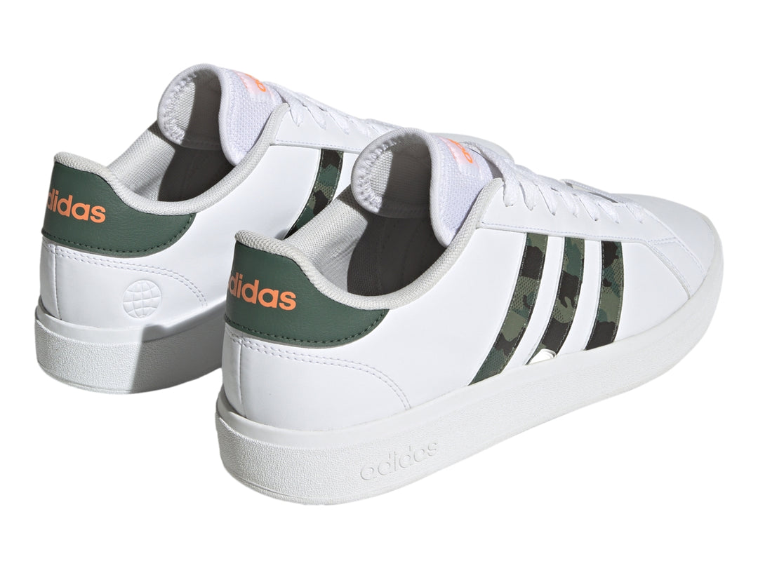 Tenis Adidas blancos con franjas laterales en patrón de camuflaje y detalles en naranja.