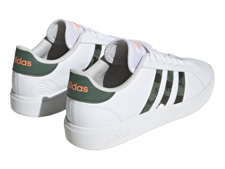 Tenis Adidas blancos con franjas laterales en patrón de camuflaje y detalles en naranja.