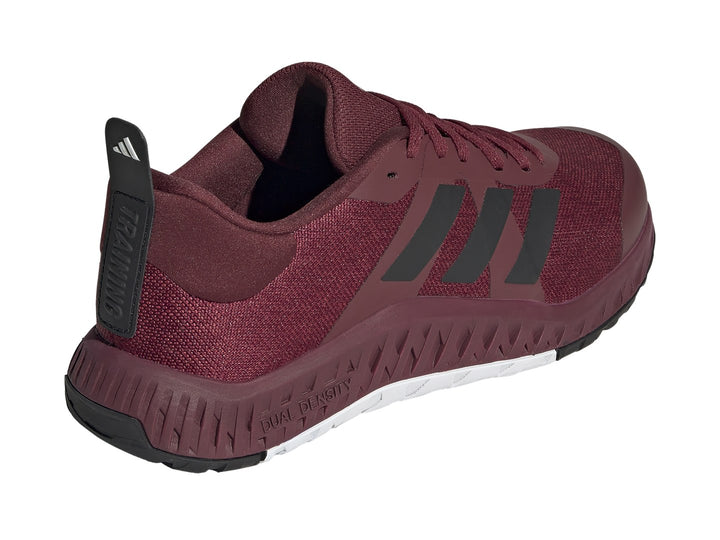 Tenis deportivos Adidas color rojo oscuro con franjas negras y suela blanca y negra.