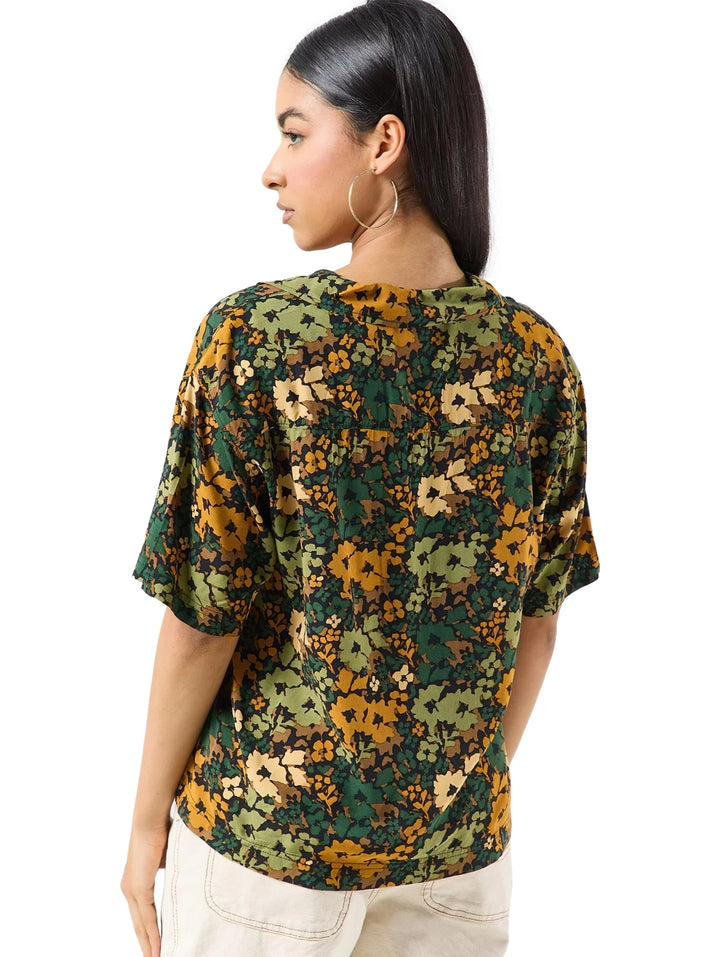 Camisa Vans de manga corta con estampado floral en tonos verde loden y amarillo, cuello en V y botones frontales.