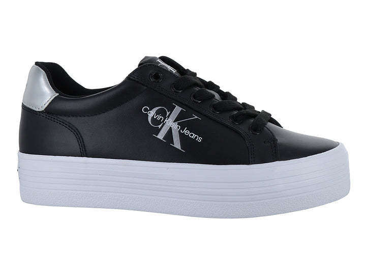 Tenis negros de plataforma Calvin Klein con suela blanca gruesa y detalles plateados.