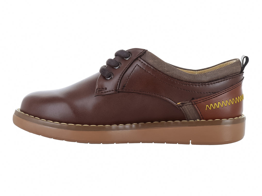 Zapato infantil modelo Rally color castaño con agujetas y suela de goma beige.