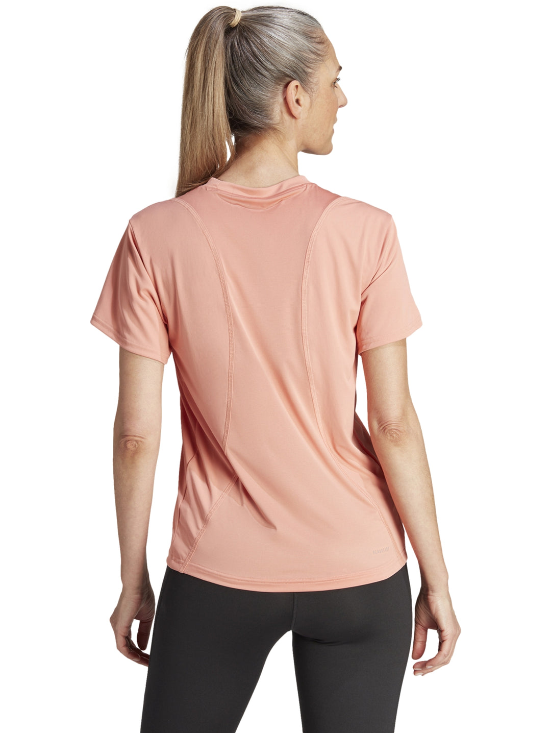Camiseta deportiva Adidas de color coral para mujer, con cuello redondo y manga corta.