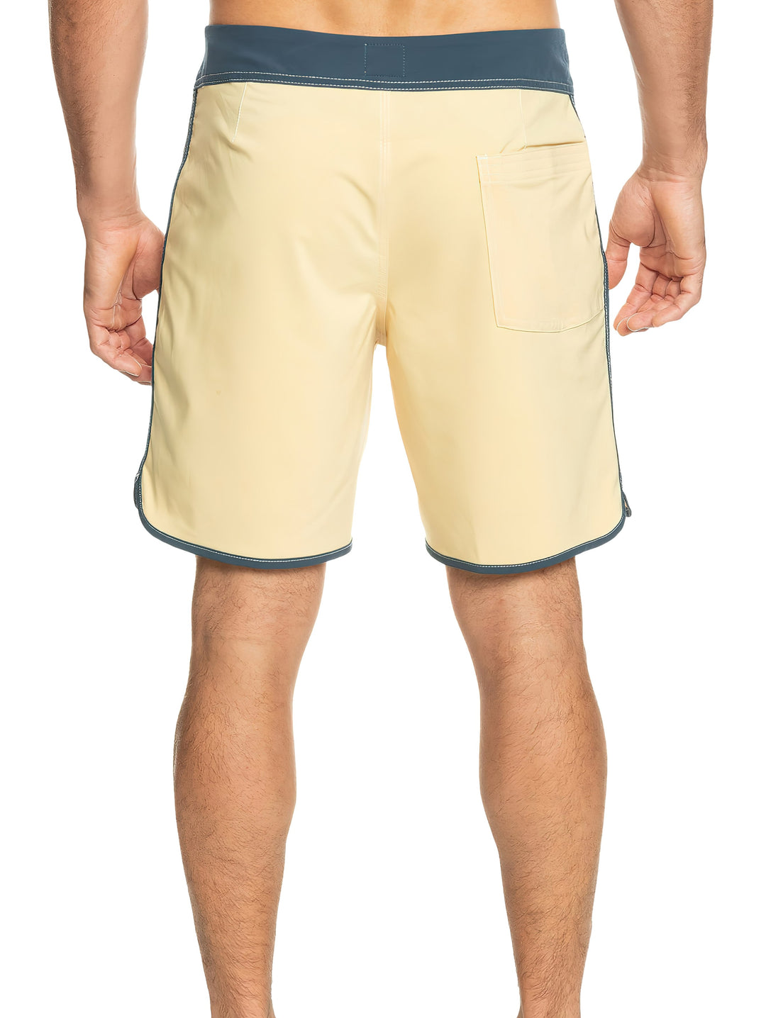 Hombre vistiendo traje de baño corto color beige con cintura y bordes en azul oscuro.