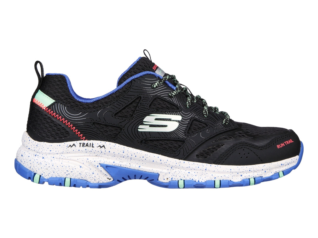 Tenis Skechers para trail running en color negro con detalles en azul y verde menta y suela blanca.