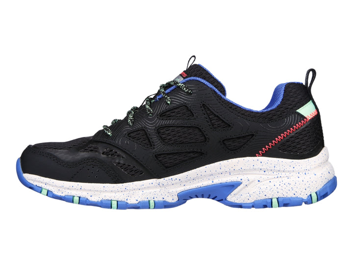 Tenis Skechers para trail running en color negro con detalles en azul y verde menta y suela blanca.