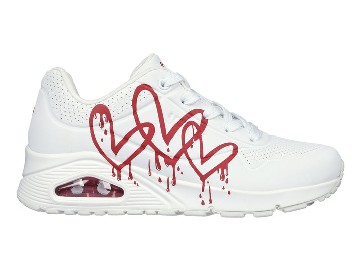Tenis Skechers blancos con diseño de corazones rojos en efecto goteo y suela amortiguada.