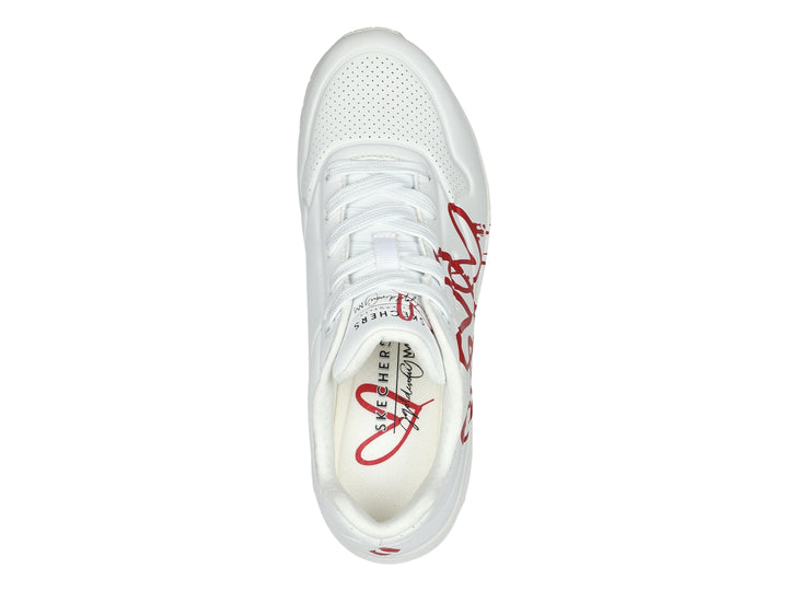 Tenis Skechers blancos con diseño de corazones rojos en efecto goteo y suela amortiguada.