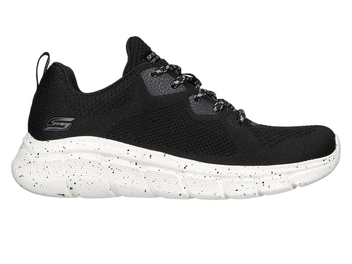 Tenis Skechers negros con suela blanca moteada y tejido transpirable.