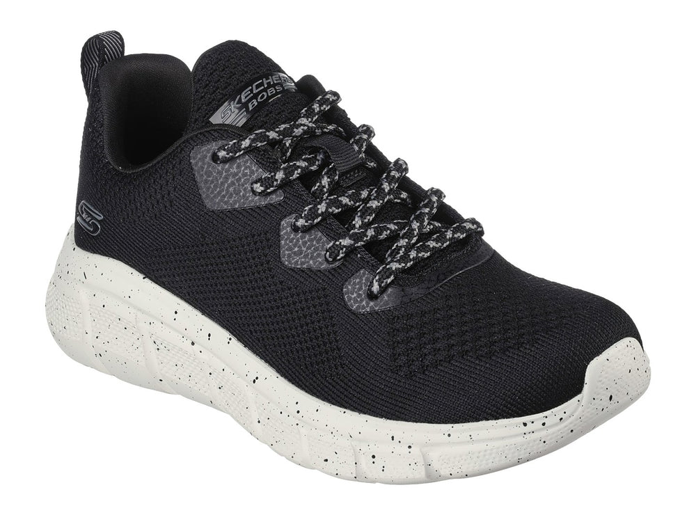 Tenis Skechers negros con suela blanca moteada y tejido transpirable.