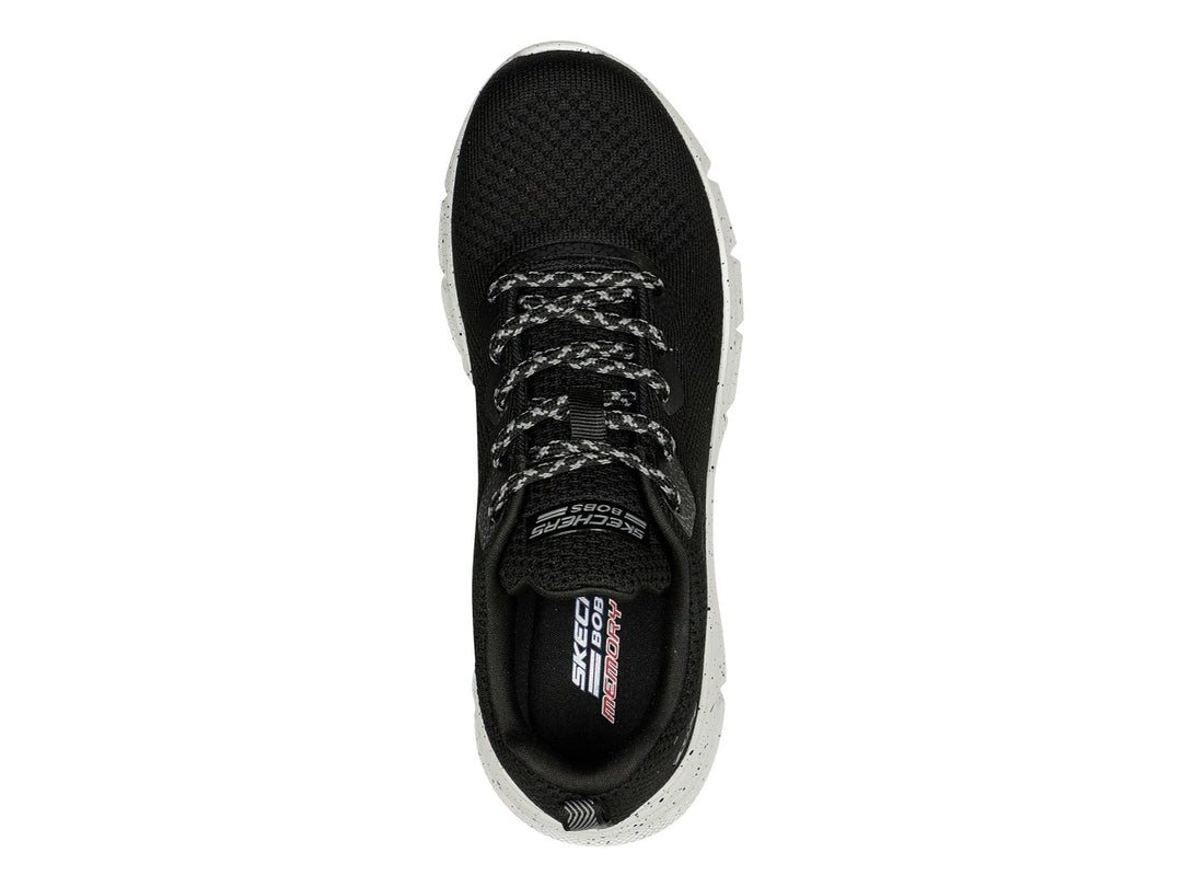 Tenis Skechers negros con suela blanca moteada y tejido transpirable.