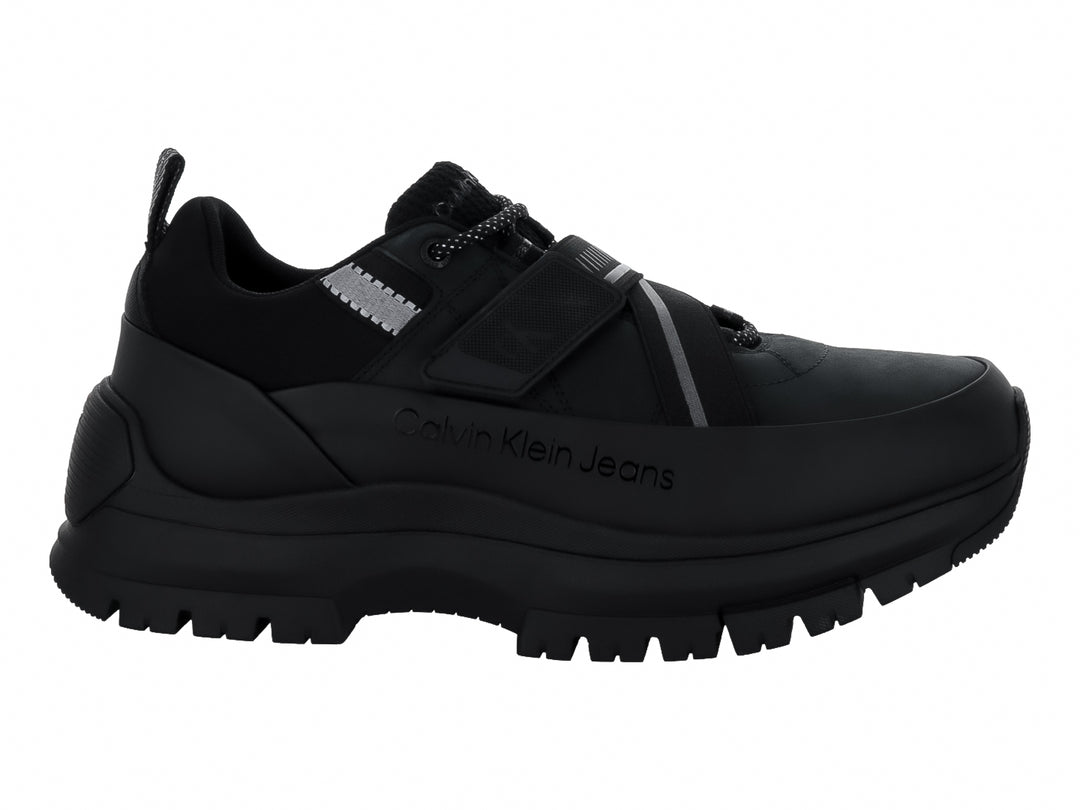 Tenis Calvin Klein negros con suela gruesa dentada, cierre de cordones y correa ajustable.
