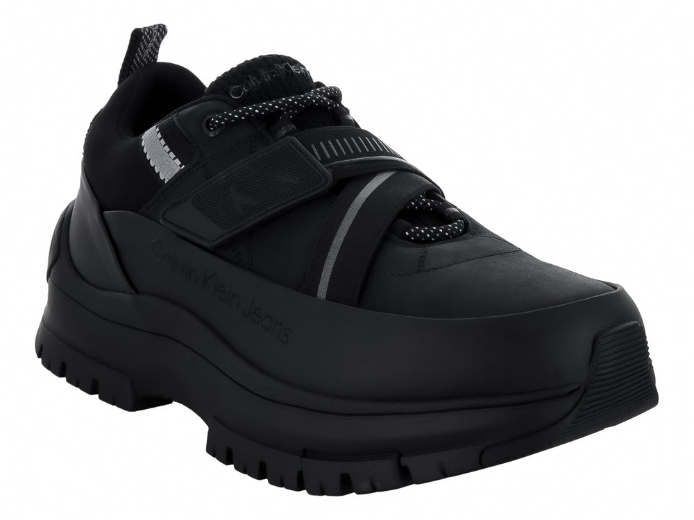 Tenis Calvin Klein negros con suela gruesa dentada, cierre de cordones y correa ajustable.