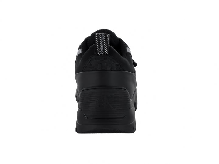 Tenis Calvin Klein negros con suela gruesa dentada, cierre de cordones y correa ajustable.