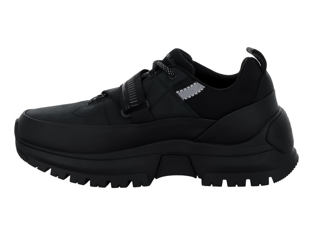 Tenis Calvin Klein negros con suela gruesa dentada, cierre de cordones y correa ajustable.