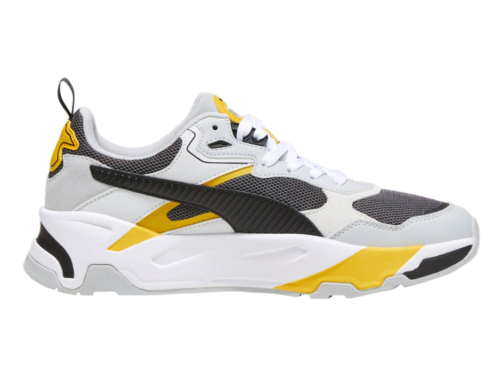 Tenis PUMA Trinity blancos y grises con detalles en amarillo y negro, diseño deportivo de suela gruesa.