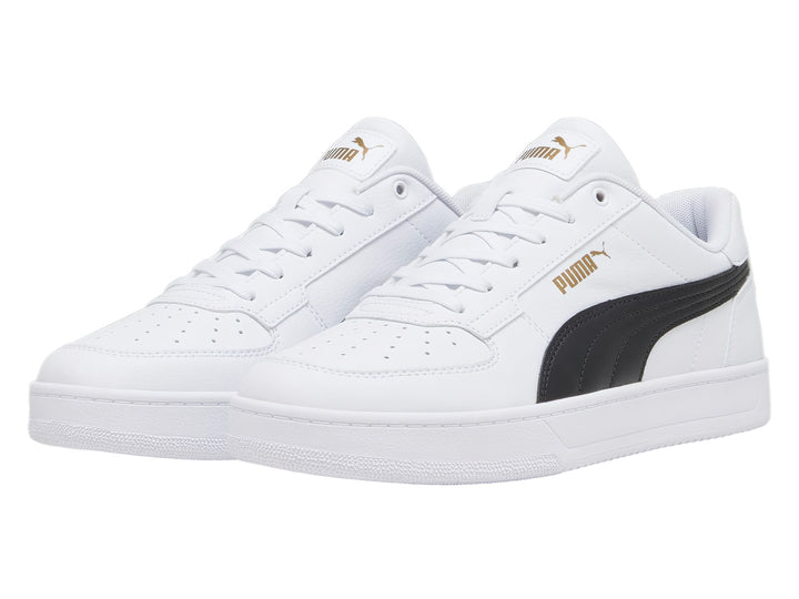 Tenis PUMA Caven 2.0 blancos con franja lateral negra y detalles dorados en la lengüeta.
