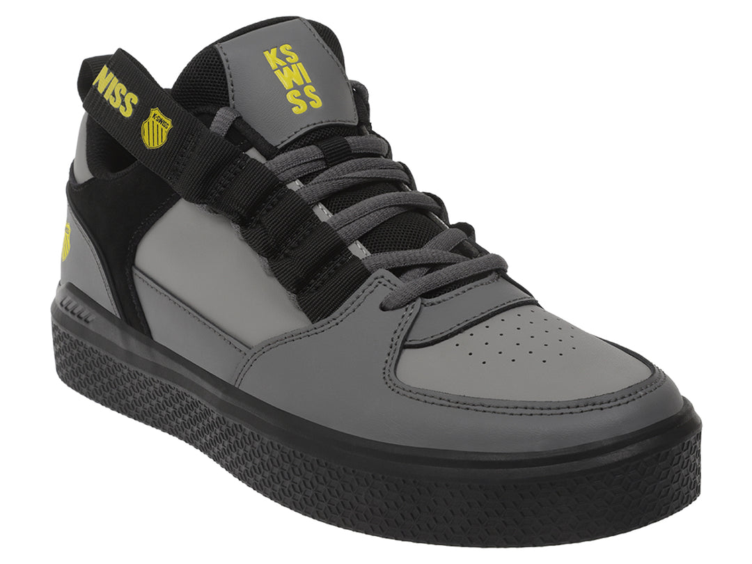 Tenis K-Swiss en color gris oscuro y negro con correa ajustable y suela negra.