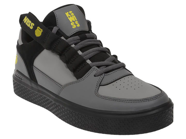 Tenis K-Swiss en color gris oscuro y negro con correa ajustable y suela negra.