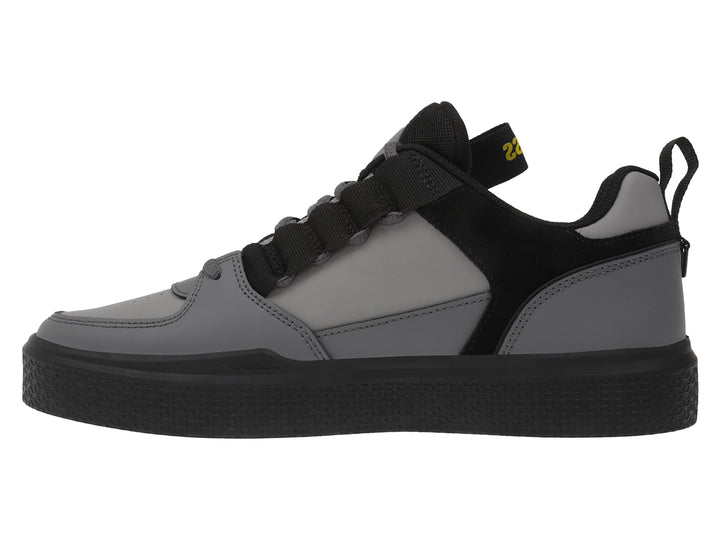 Tenis K-Swiss en color gris oscuro y negro con correa ajustable y suela negra.