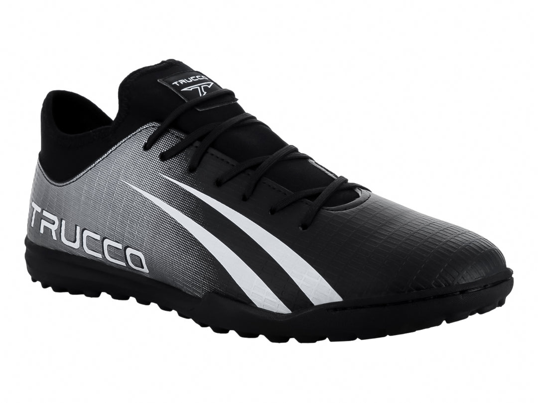 Zapato de fútbol Leon Trucco en color negro y plateado con franjas blancas laterales y suela negra.