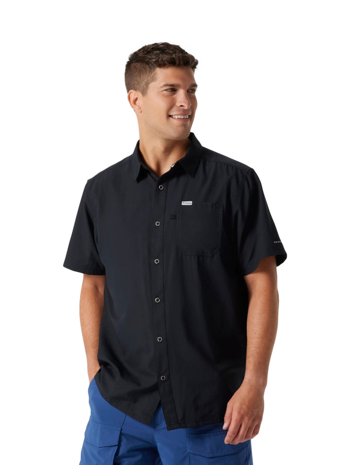 Hombre vistiendo una camisa Columbia de manga corta color negro con botones y bolsillo frontal.