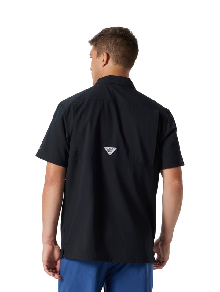 Hombre vistiendo una camisa Columbia de manga corta color negro con botones y bolsillo frontal.