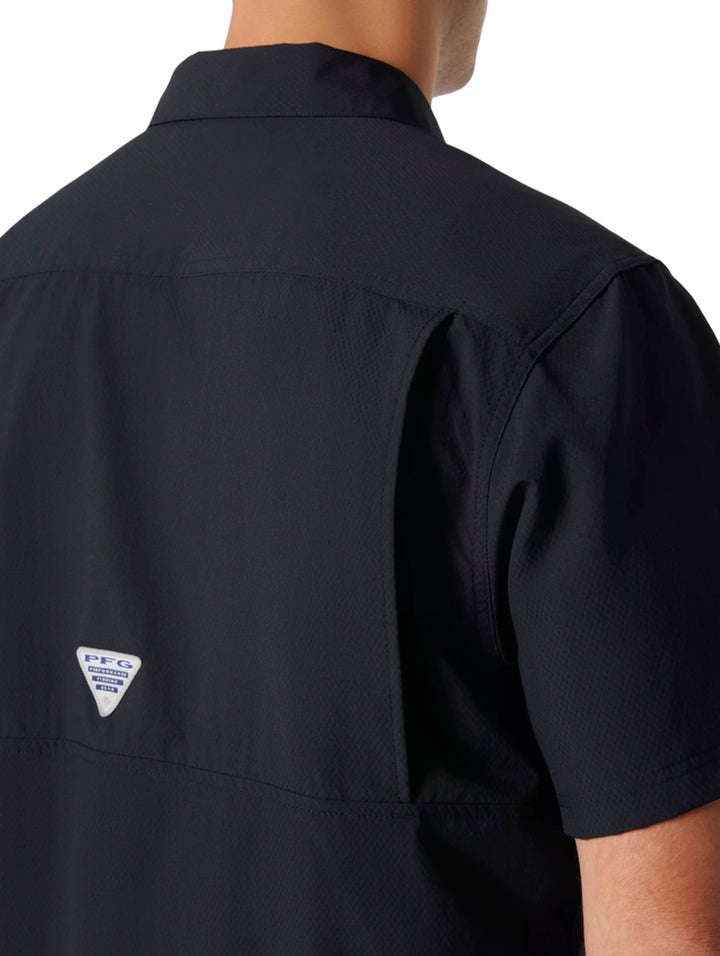 Hombre vistiendo una camisa Columbia de manga corta color negro con botones y bolsillo frontal.