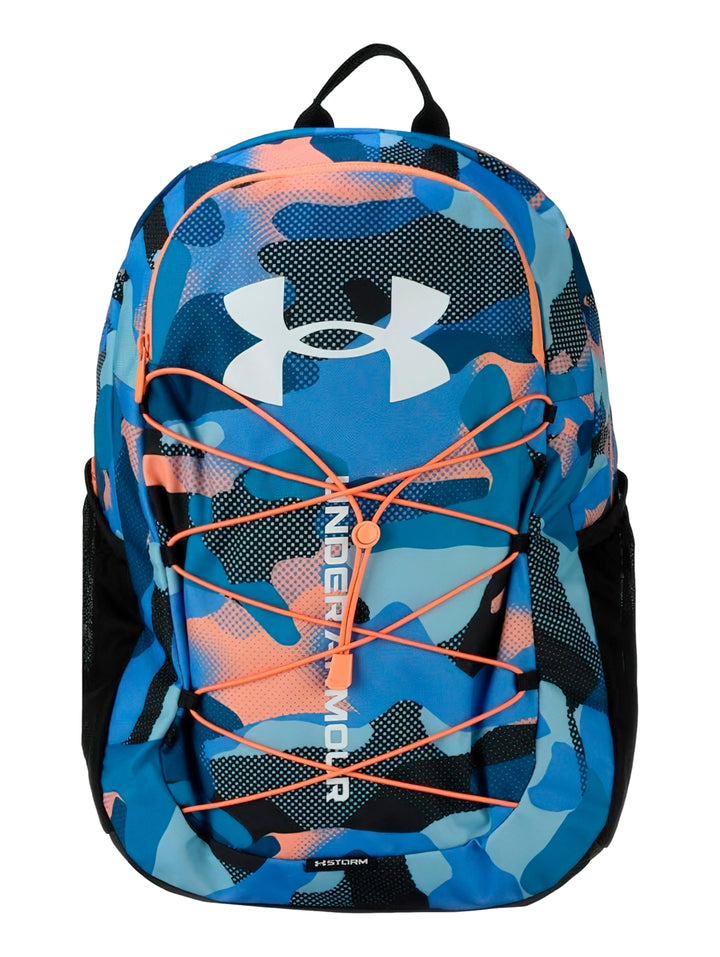 Mochila Under Armour con estampado de camuflaje en tonos azul, negro y naranja, con cordones frontales decorativos.