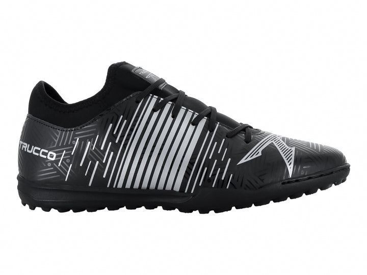 Zapato de fútbol Leon Trucco color negro con detalles lineales en plata y suela para césped sintético.