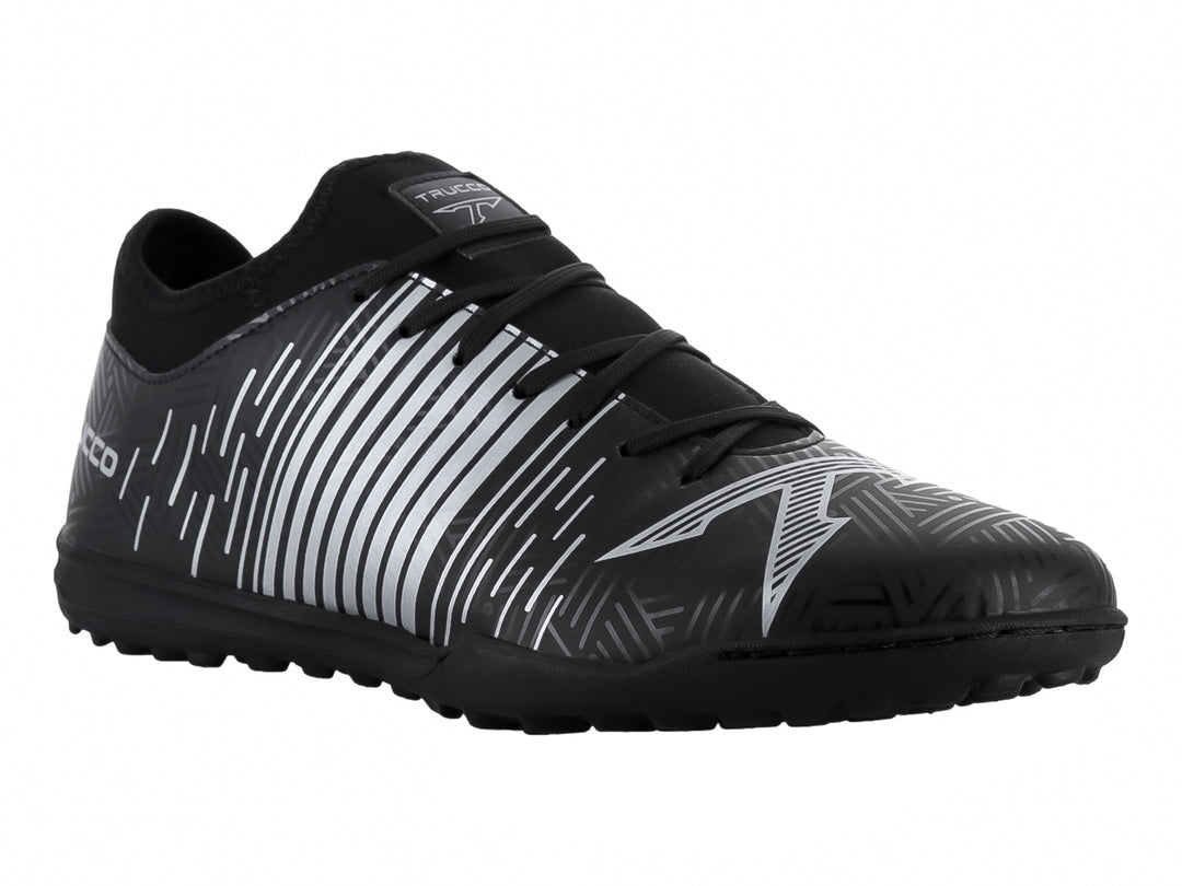 Zapato de fútbol Leon Trucco color negro con detalles lineales en plata y suela para césped sintético.