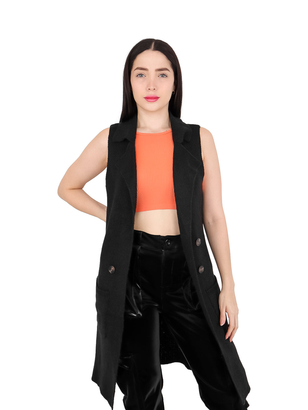 Mujer vistiendo un chaleco largo de color negro con botones, combinado con top naranja y pantalones negros.