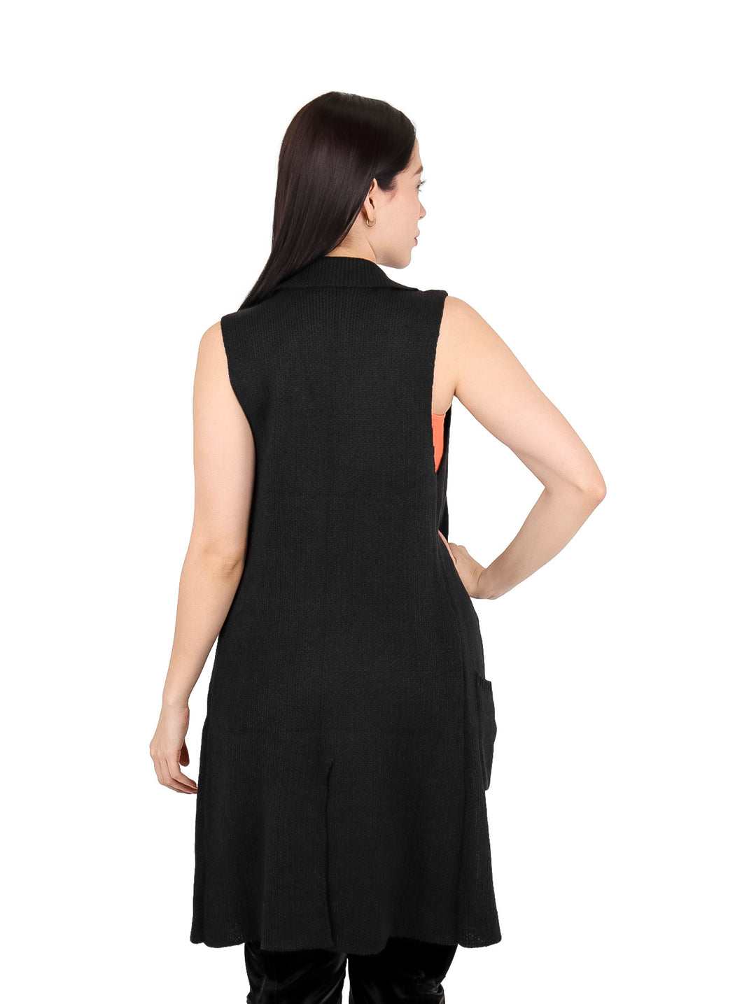 Mujer vistiendo un chaleco largo de color negro con botones, combinado con top naranja y pantalones negros.