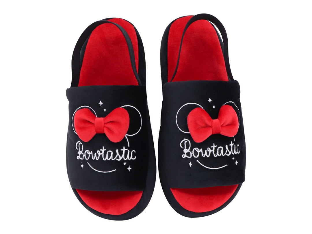 Par de pantuflas negras y rojas con un moño rojo decorativo y texto bordado en blanco.
