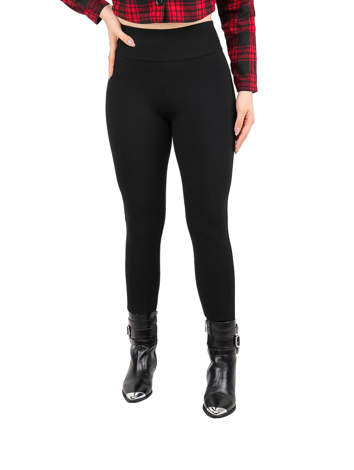 Mujer vistiendo leggings negros de pretina ancha y botas negras.