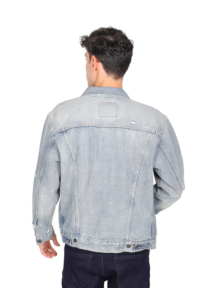 Hombre modelando una chaqueta de mezclilla azul claro de corte relajado.