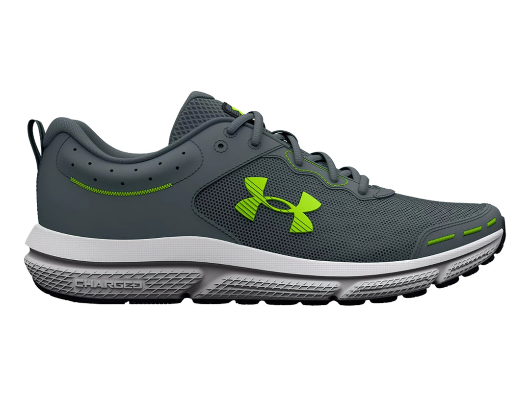 Tenis deportivos Under Armour Charged Assert 10 en color gris con detalles en verde neón y suela blanca.