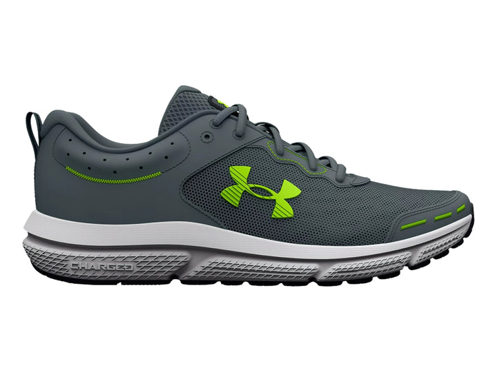 Tenis deportivos Under Armour Charged Assert 10 en color gris con detalles en verde neón y suela blanca.