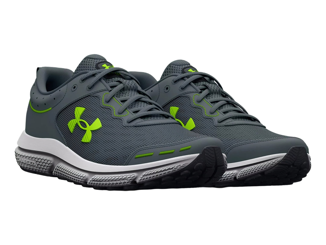 Tenis deportivos Under Armour Charged Assert 10 en color gris con detalles en verde neón y suela blanca.