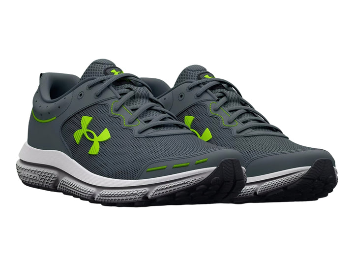 Tenis deportivos Under Armour Charged Assert 10 en color gris con detalles en verde neón y suela blanca.