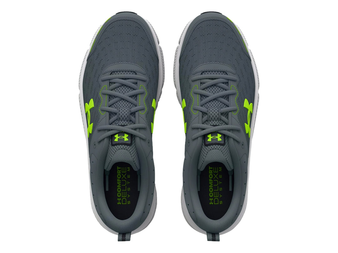 Tenis deportivos Under Armour Charged Assert 10 en color gris con detalles en verde neón y suela blanca.