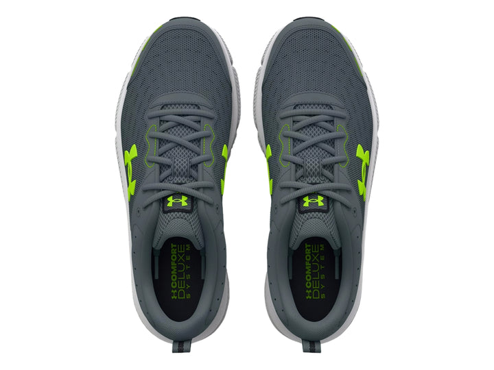 Tenis deportivos Under Armour Charged Assert 10 en color gris con detalles en verde neón y suela blanca.