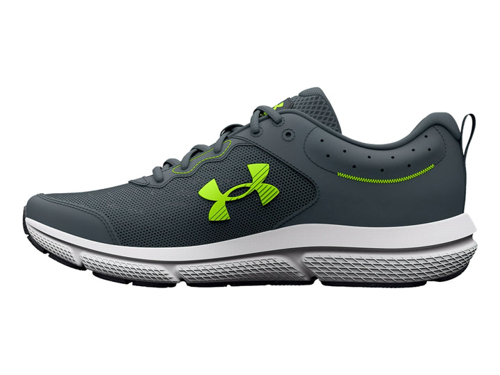 Tenis deportivos Under Armour Charged Assert 10 en color gris con detalles en verde neón y suela blanca.