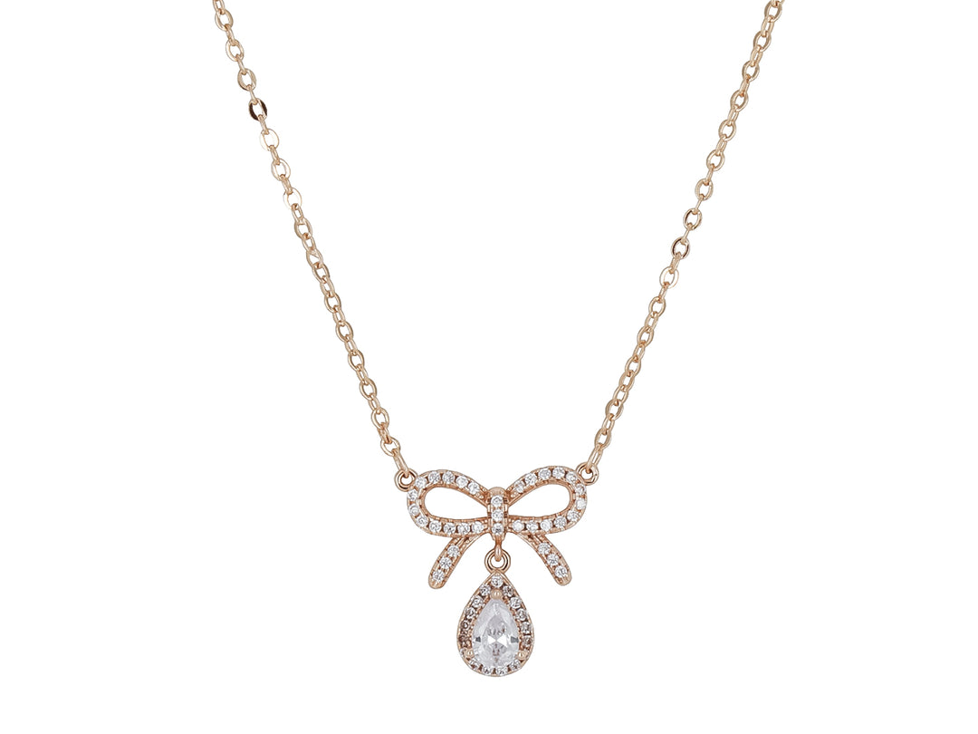 Collar dorado de la marca ROZE con dije en forma de moño adornado con cristales y una piedra central en forma de gota.
