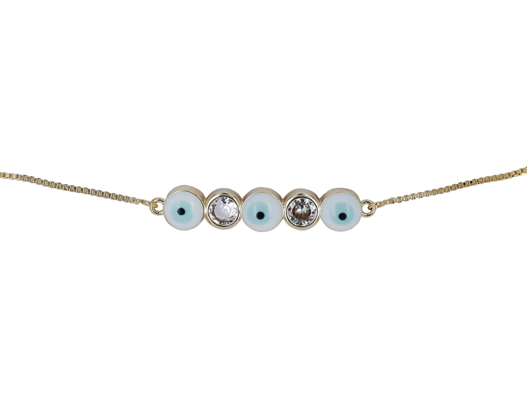 Pulsera de cadena dorada con cinco dijes circulares, incluyendo ojos turcos y cristales brillantes.